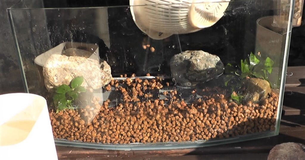 石や水草を配置してから底面ろ過フィルター上に赤玉土を入れていきます